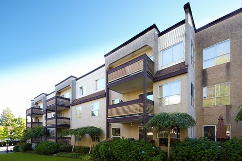 a row of apartment buildings with green grass and trees